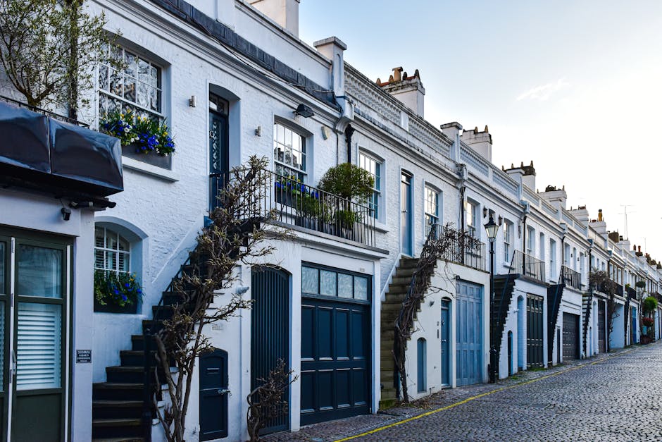 A wide residential street in Chiswick lined with white stucco Victorian-style terraced houses, each with decorative architectural features such as bay windows and balconies. The street is filled with 